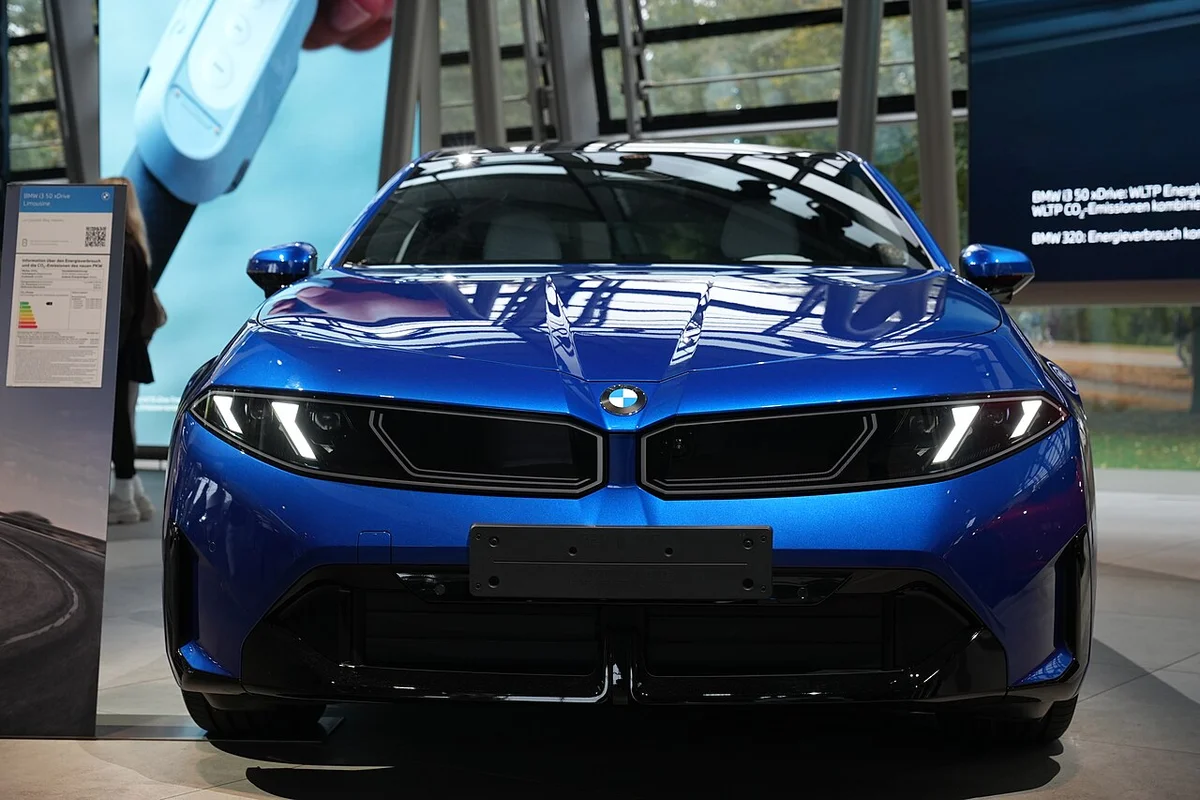 BMW 벨트에 전시된 파란색 BMW i3 50 xDrive의 정면, 얇은 헤드램프와 이중 키드니 그릴이 보인다