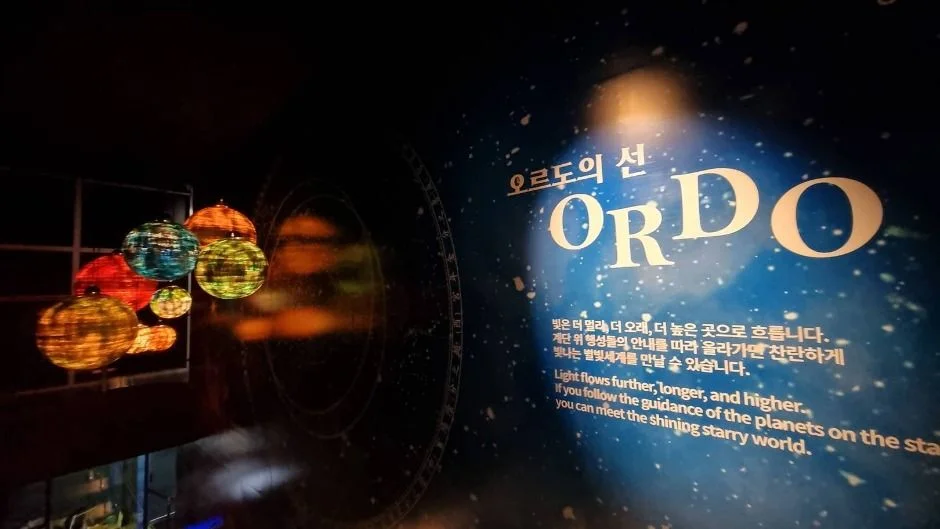 행성 모형 조명과 ORDO 문구가 보이는 전시 벽면
