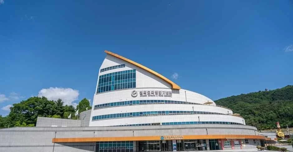 푸른 하늘 아래 곡선 지붕을 가진 칠곡호국평화기념관 외관과 앞 광장