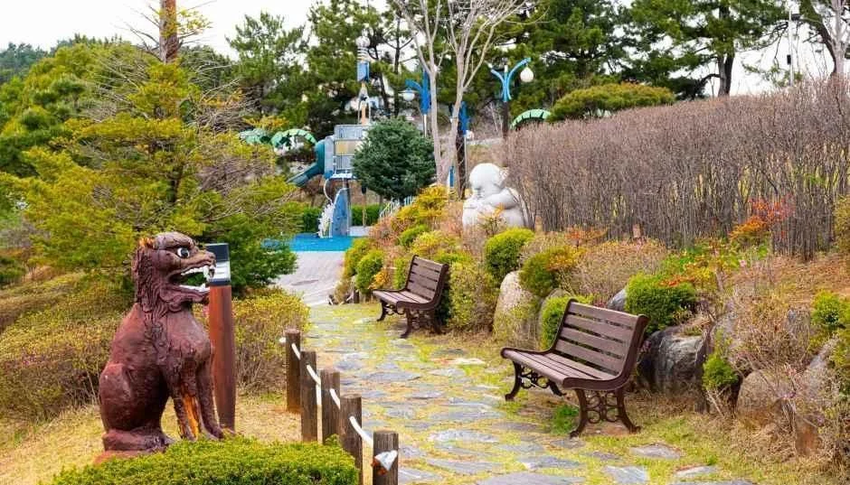돌 사자상과 벤치가 놓인 공원 산책길
