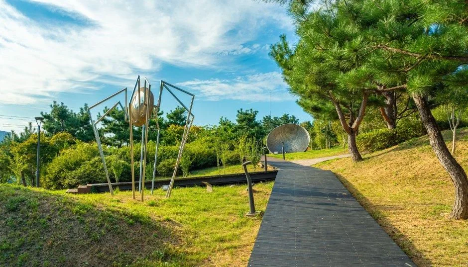 소나무 사이 산책로 옆에 선 금속 조형물