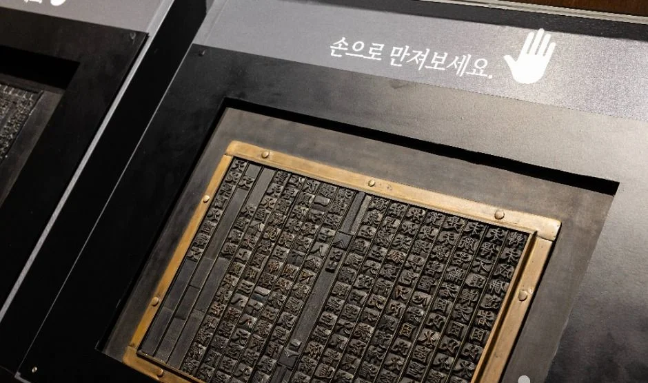 손으로 만져보세요 안내와 함께 놓인 활자판 전시