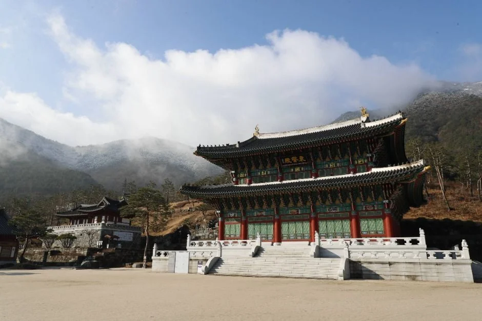 맑은 하늘 아래 산자락 앞에 선 2층 전각