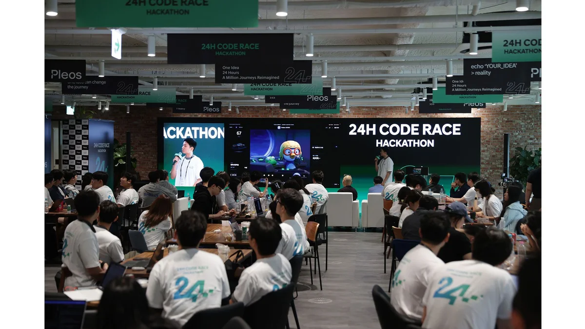 24H CODE RACE HACKATHON 현수막 아래에서 참가자들이 모여 앉아 발표를 듣고 있는 행사장