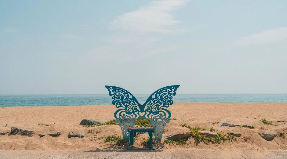 모래 해변 위에 놓인 푸른 나비 모양 의자