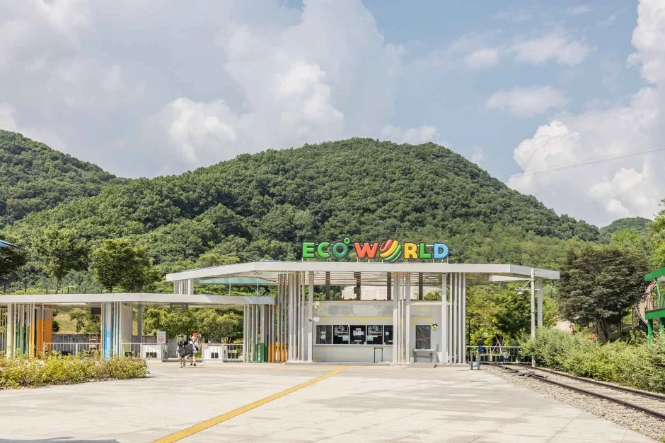 ECO WORLD 글씨가 보이는 문경에코월드 정문과 매표소 건물, 뒤로 숲이 우거진 산