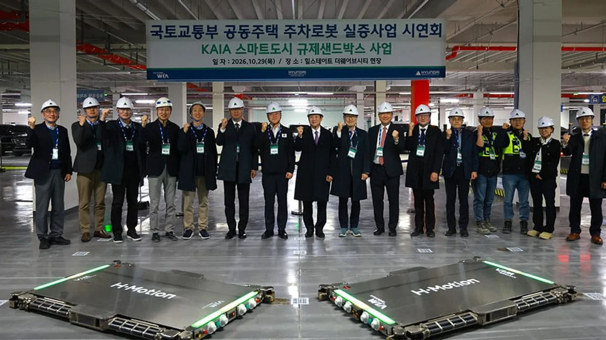 지하 주차장 바닥의 주차로봇 두 대 뒤로 시연회 참석자들이 줄지어 선 단체 사진
