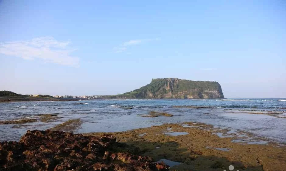 썰물에 드러난 바위 너머로 성산일출봉이 보이는 광치기해변