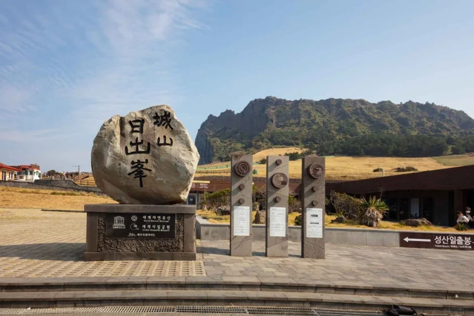 성산일출봉 한자가 새겨진 표석과 안내 조형물, 뒤로 성산일출봉이 보이는 입구 일대