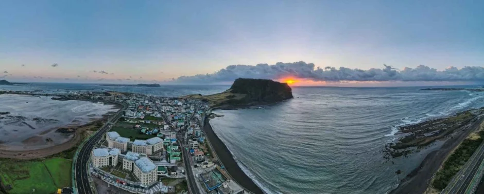 성산 마을과 해안, 성산일출봉 위로 해가 뜨는 항공 파노라마