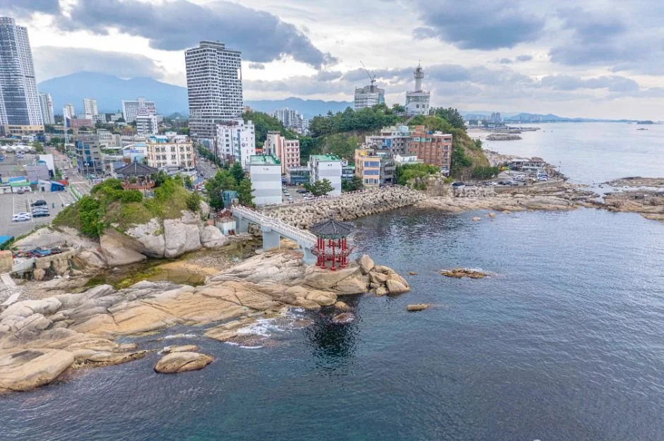 속초 시내와 산세를 배경으로 바다 위 암반에 세워진 영금정 정자를 내려다본 모습