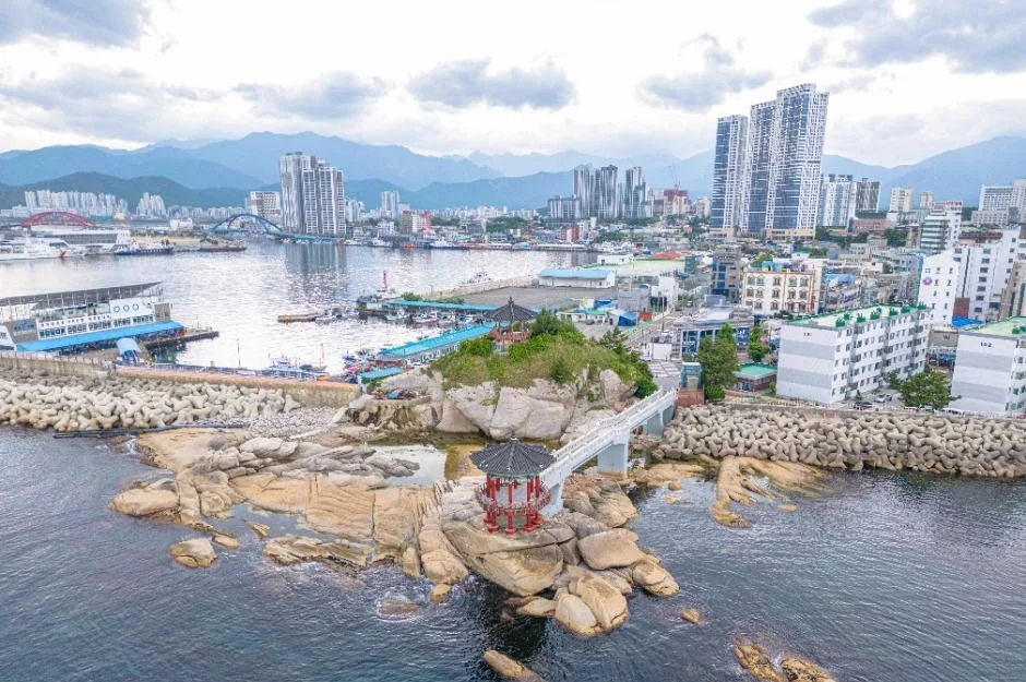 속초항과 시내, 먼 산을 배경으로 바다 위 암반에 세워진 영금정 정자