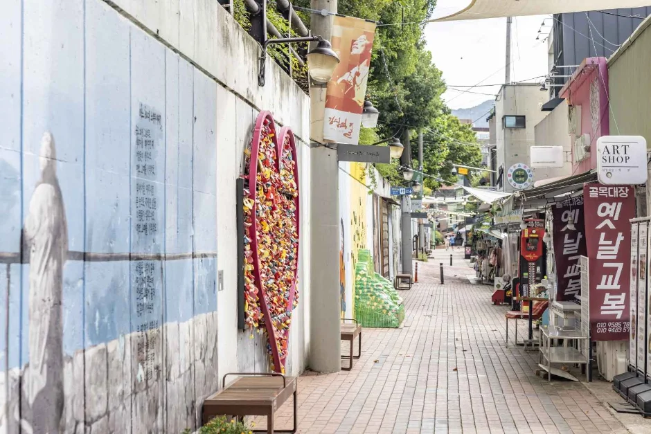 벽화가 이어진 벽돌 바닥 골목과 하트 장식, 가게 간판