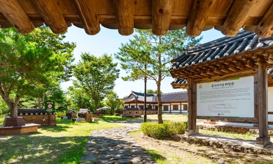 안내판과 한옥 건물이 보이는 마을 입구 풍경
