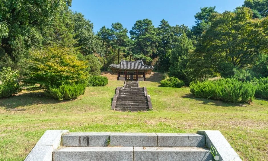 잔디밭 위 계단 끝에 작은 정자가 서 있는 모습