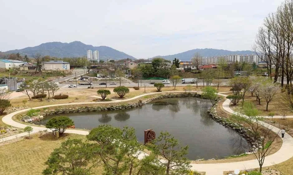 연못과 산책로, 멀리 산이 보이는 공원 전경