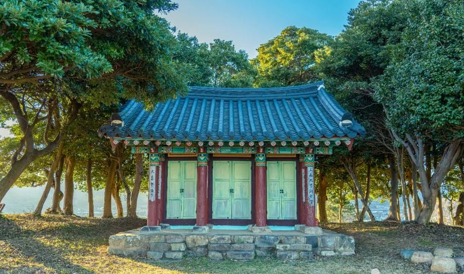 소나무 사이로 보이는 푸른 기와의 건물과 붉은 기둥