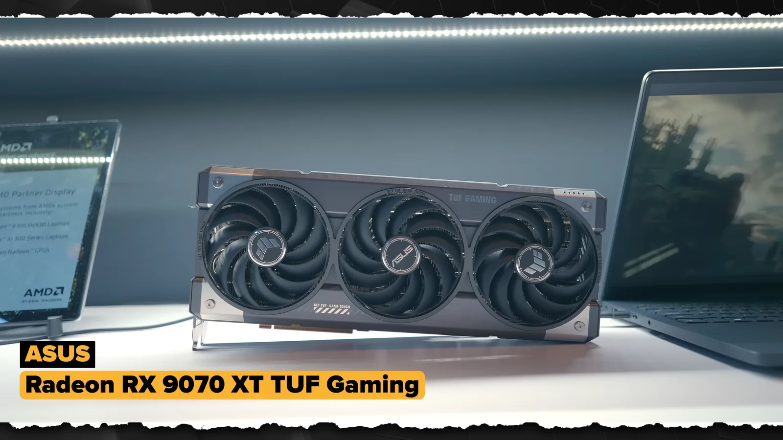 ASUS TUF 게이밍 라데온 RX 9070 XT 그래픽카드 제품 사진 - 검은색과 회색 톤의 대형 쿨러가 장착된 그래픽카드가 어두운 배경 위에 놓인 모습