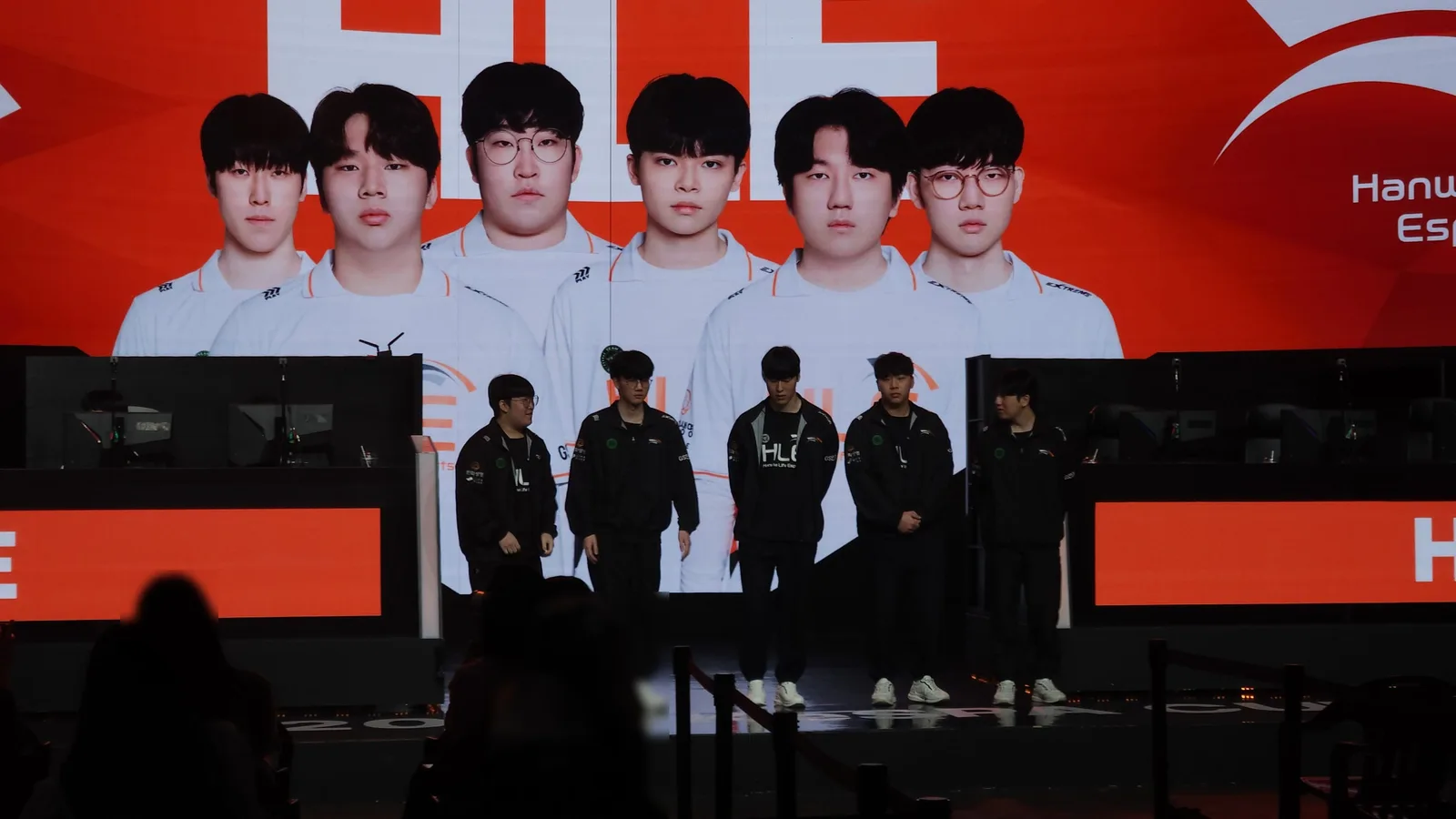 대형 스크린에 한화생명e스포츠 선수 6명의 얼굴이 뜬 무대 앞에 유니폼 재킷 차림의 선수 5명이 서 있는 모습