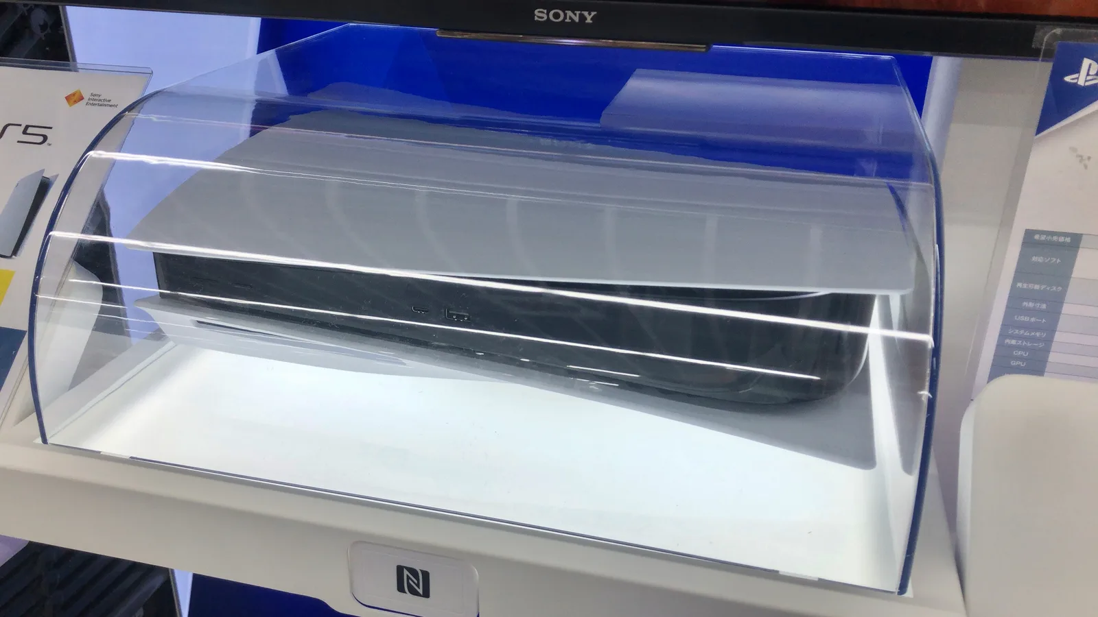 투명한 아크릴 케이스 안에 놓인 흰색 PS5 본체. 위쪽에 SONY 로고가 보인다