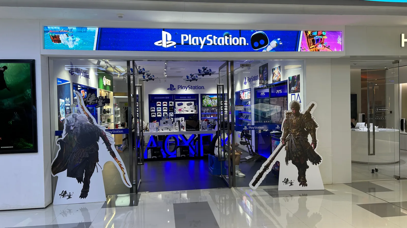 PlayStation 로고가 걸린 매장 입구. 양옆에 검은 신화 오공 캐릭터 입간판이 서 있고 안쪽에 컨트롤러와 게임 패키지가 진열돼 있다